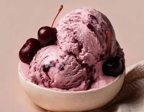 Delicious cherry ice cream in a bowl topped with fresh cherries