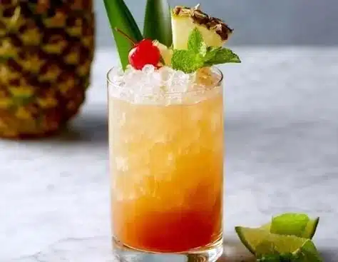 A classic Mai Tai cocktail garnished with mint and lime on a tropical background.