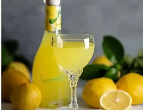 Homemade limoncello served in a glass with lemons and a rustic background.